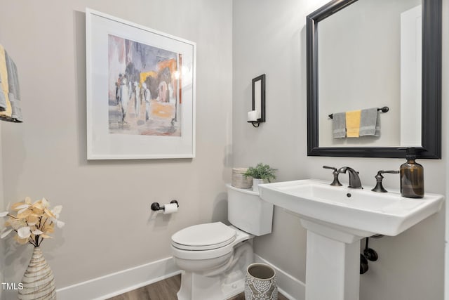 half bath featuring toilet, baseboards, and wood finished floors