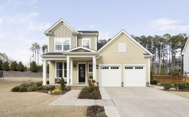 view of front of property featuring concrete driveway, a porch, board and batten siding, and fence