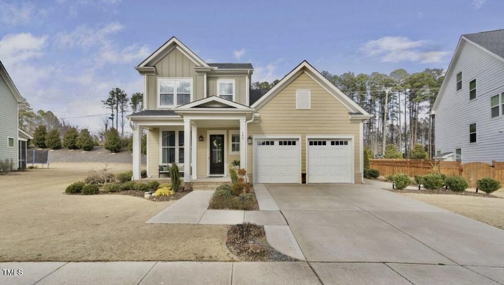 104 Sage Oak Ln, Holly Springs, NC 27540 - view of front facade with fence, driveway, covered porch, a garage, and board and batten siding