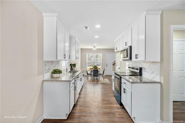 kitchen with stainless steel appliances, wood finished floors, a sink, and visible vents