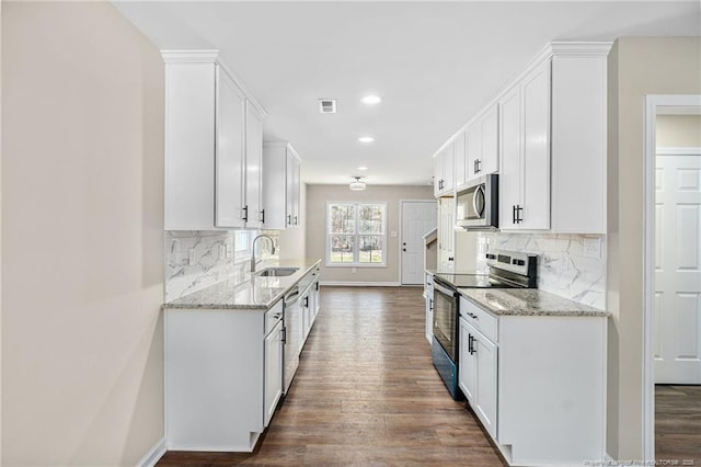 kitchen with appliances with stainless steel finishes, visible vents, a sink, and dark wood-style floors