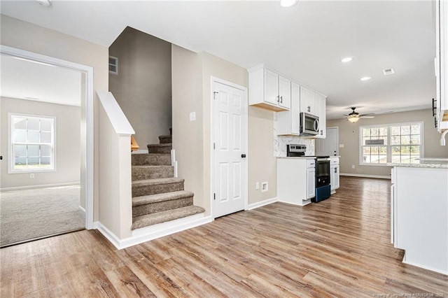 kitchen featuring range with electric cooktop, stainless steel microwave, light wood-style floors, and white cabinets