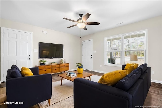 living area with visible vents, ceiling fan, baseboards, and wood finished floors