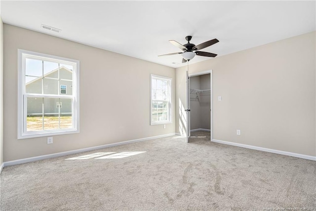 carpeted empty room featuring ceiling fan, visible vents, and baseboards