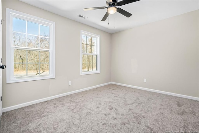 spare room with carpet, visible vents, ceiling fan, and baseboards