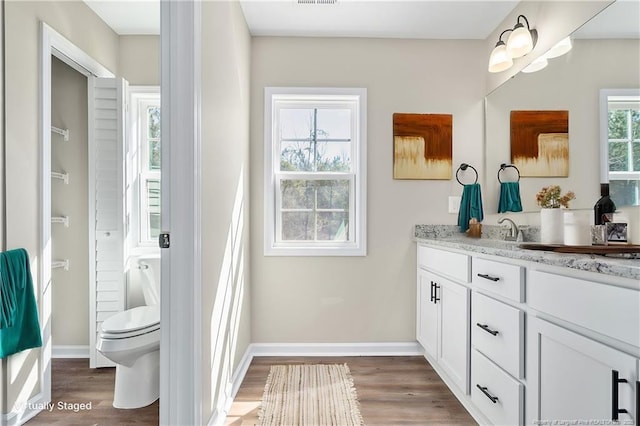 bathroom with toilet, baseboards, wood finished floors, and vanity