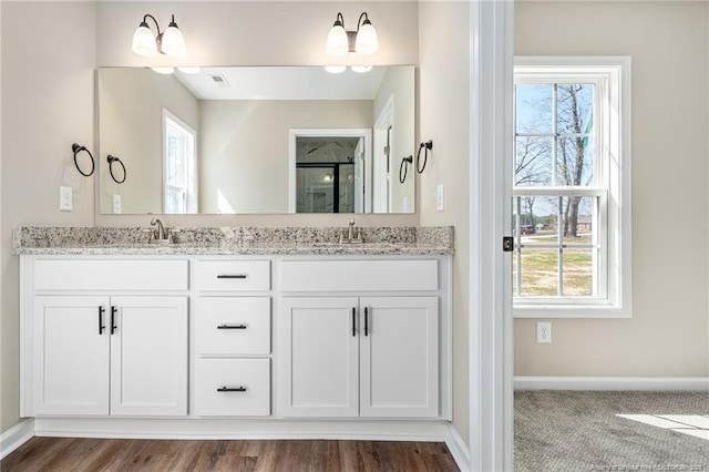 bathroom with double vanity, visible vents, baseboards, and a sink