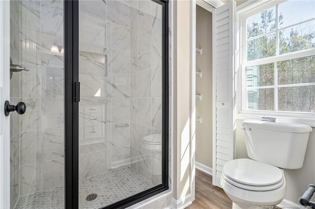 full bathroom featuring toilet, a stall shower, baseboards, and wood finished floors