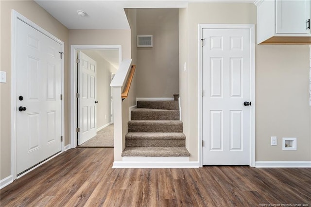 foyer entrance with dark wood-style floors, baseboards, stairs, and visible vents