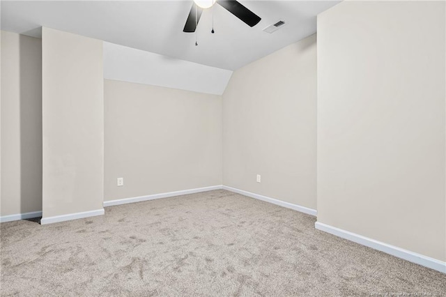 carpeted empty room featuring vaulted ceiling, a ceiling fan, visible vents, and baseboards