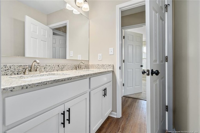 bathroom featuring double vanity, a sink, and wood finished floors