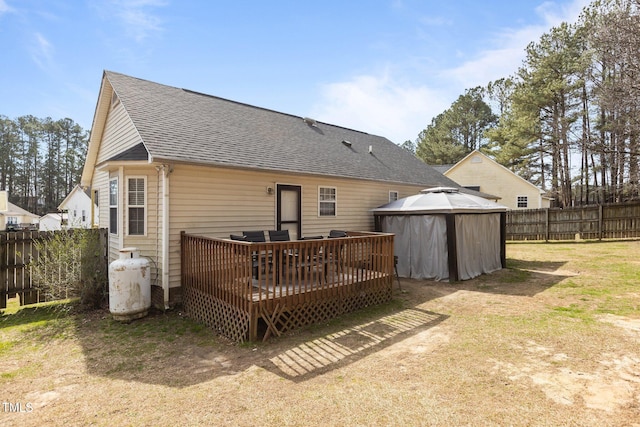 back of property with a deck, fence private yard, and roof with shingles