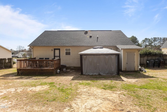 rear view of property featuring fence, roof with shingles, and a wooden deck