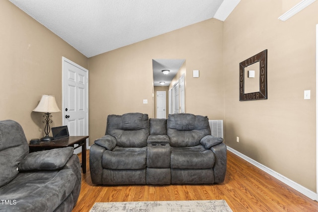 living area with visible vents, baseboards, wood finished floors, and vaulted ceiling