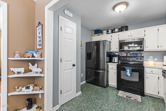 kitchen with a textured ceiling, appliances with stainless steel finishes, white cabinets, dark floors, and light countertops