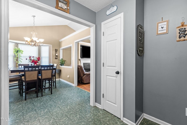 dining space featuring a chandelier, lofted ceiling, baseboards, and dark floors