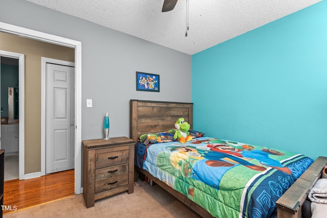 bedroom featuring ceiling fan, light carpet, and a textured ceiling