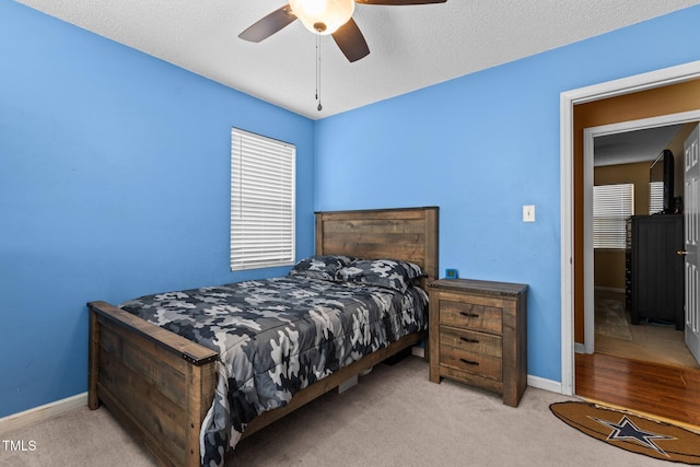 carpeted bedroom featuring a ceiling fan, baseboards, and a textured ceiling