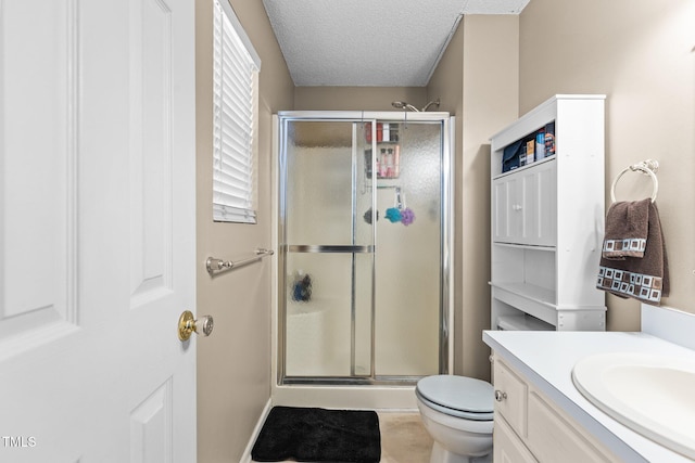 full bathroom featuring a textured ceiling, a stall shower, vanity, and toilet