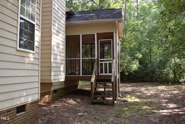 view of side of property with roof with shingles, crawl space, and a sunroom