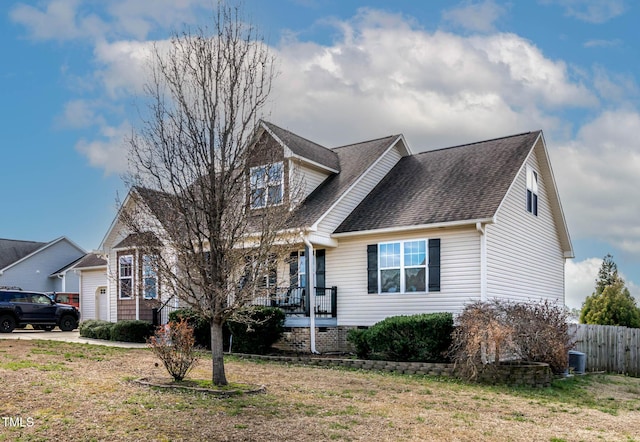 view of front of house featuring cooling unit, fence, covered porch, a shingled roof, and a front lawn