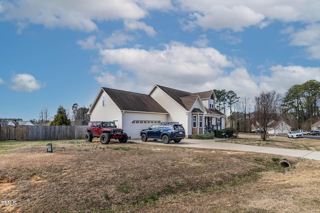 view of side of home with concrete driveway, an attached garage, and fence