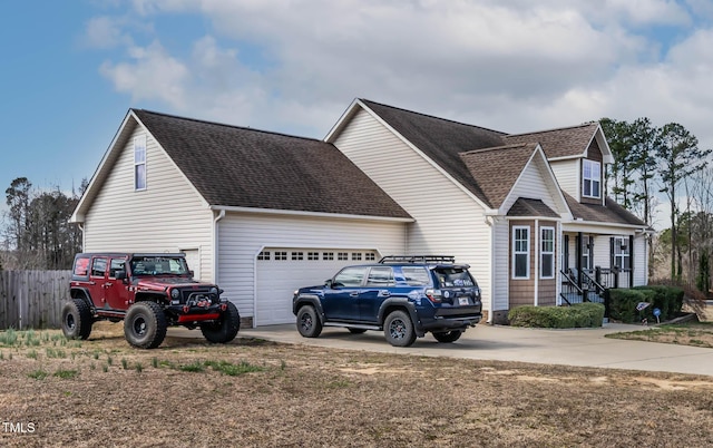 view of front of home with concrete driveway, fence, a garage, and roof with shingles