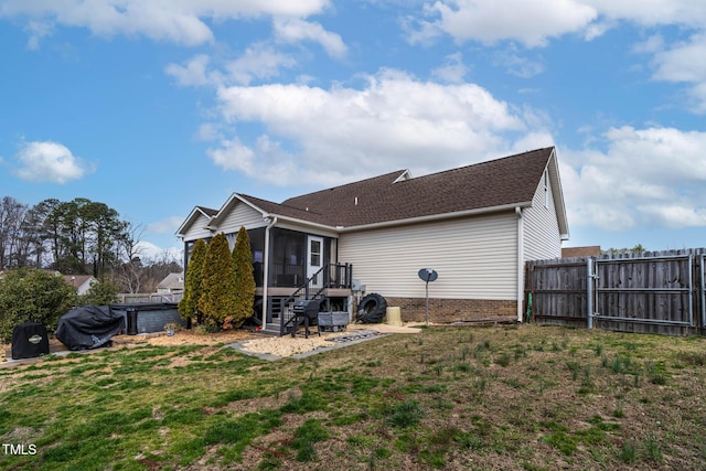 back of property with fence, a yard, and a sunroom