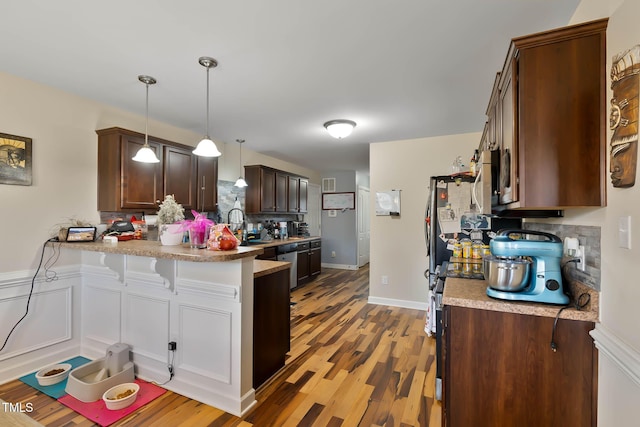 kitchen featuring a breakfast bar, a peninsula, light wood-style flooring, dark brown cabinets, and dishwasher