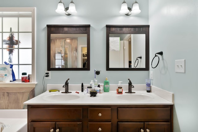 full bath featuring an inviting chandelier, double vanity, a bathtub, and a sink