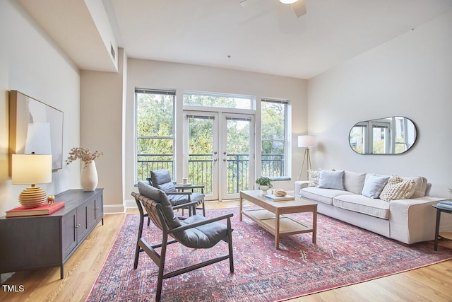 living area with a ceiling fan, french doors, light wood-style flooring, and baseboards