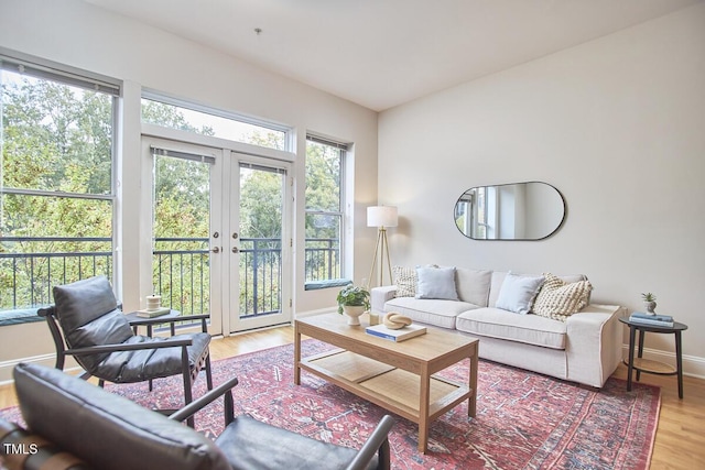 living area with light wood finished floors, french doors, and baseboards