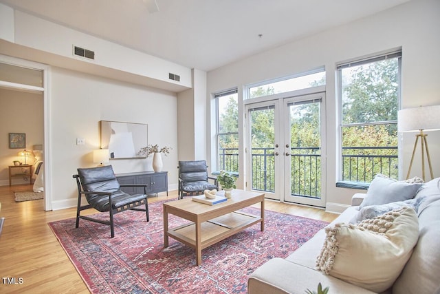 living room with french doors, light wood-type flooring, visible vents, and baseboards