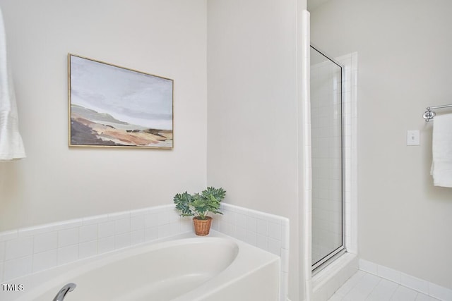 bathroom with tile patterned flooring, a garden tub, a shower stall, and baseboards