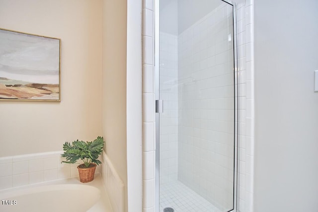 bathroom with a stall shower and a garden tub