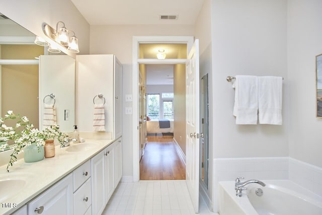 ensuite bathroom featuring double vanity, connected bathroom, a garden tub, tile patterned flooring, and a sink