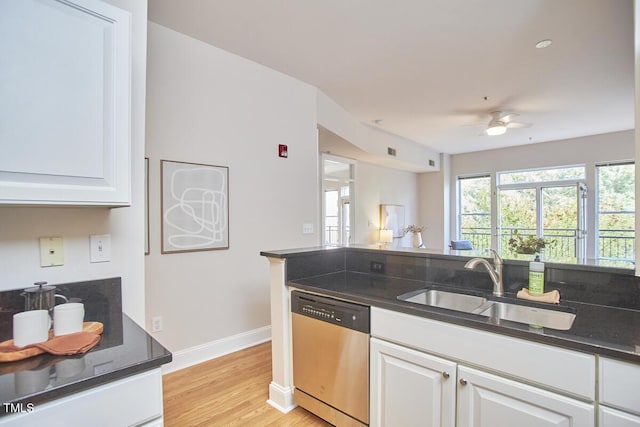 kitchen featuring dark countertops, white cabinets, dishwasher, and a sink