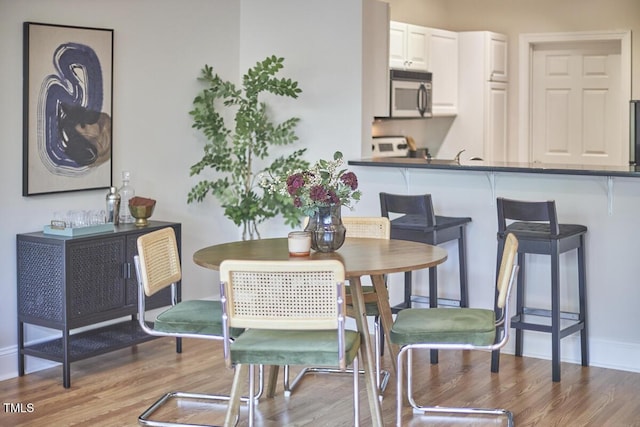 dining space with light wood-type flooring and baseboards