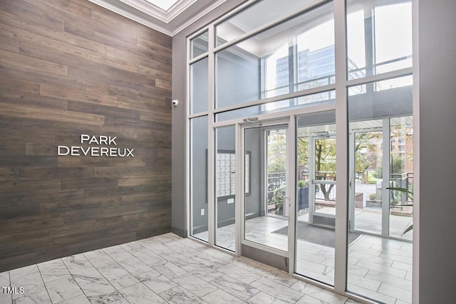 interior space with ornamental molding, marble finish floor, wood walls, and a high ceiling