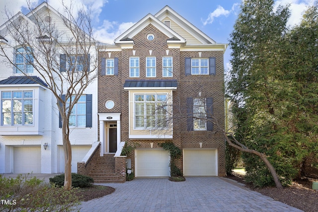 view of front of home featuring an attached garage, a standing seam roof, decorative driveway, and brick siding