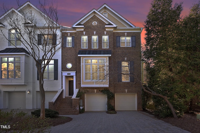 view of front of house featuring a garage, metal roof, a standing seam roof, decorative driveway, and brick siding