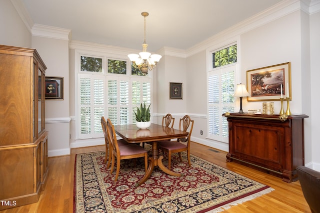 dining space with light wood finished floors, baseboards, ornamental molding, and an inviting chandelier