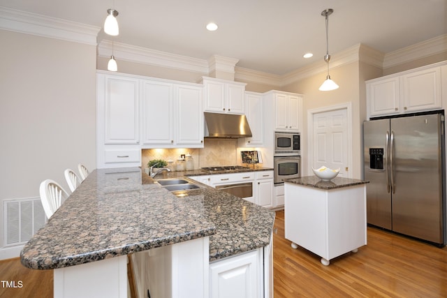 kitchen featuring under cabinet range hood, a sink, visible vents, appliances with stainless steel finishes, and a center island