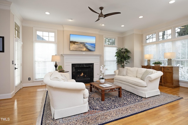 living area with recessed lighting, ornamental molding, a high end fireplace, light wood-style floors, and baseboards