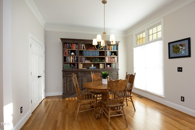 dining space with baseboards, ornamental molding, wood finished floors, and an inviting chandelier