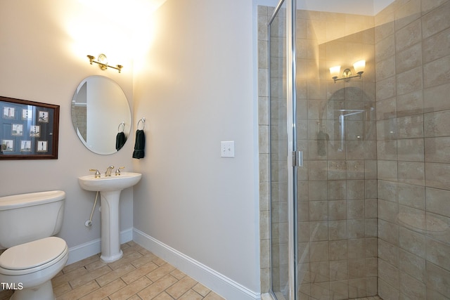 bathroom featuring baseboards, a sink, a shower stall, and toilet