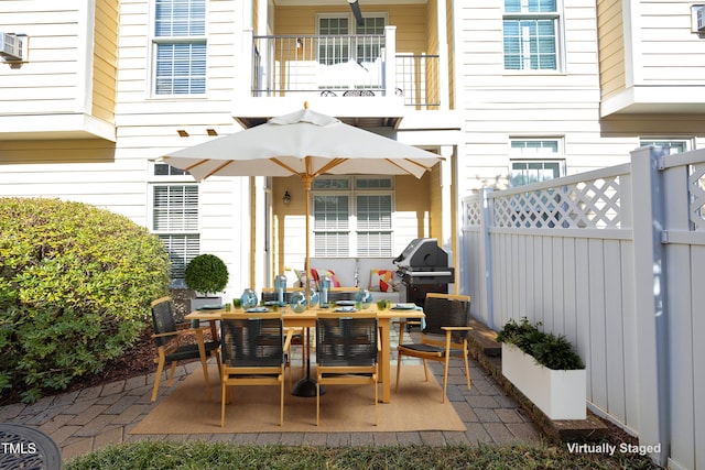 view of patio / terrace with a balcony, fence, area for grilling, and outdoor dining space