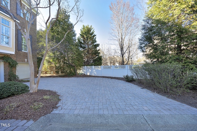 exterior space featuring a garage, decorative driveway, and fence