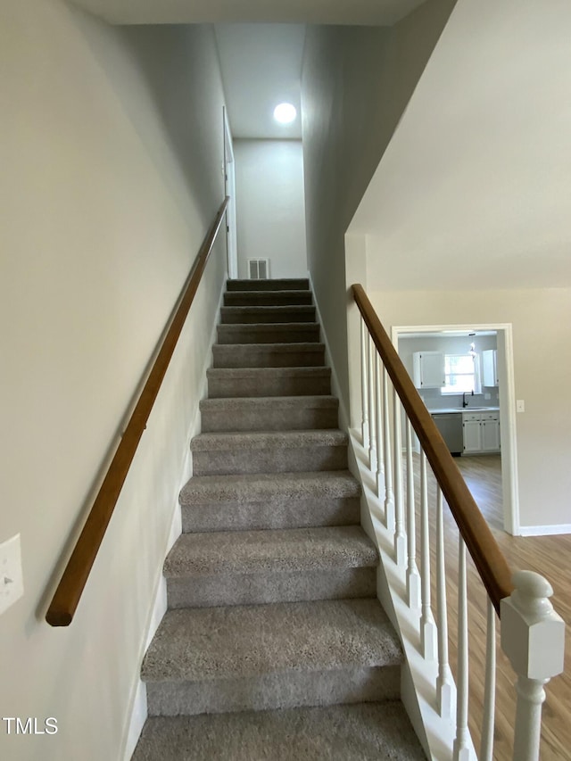 staircase with visible vents and wood finished floors