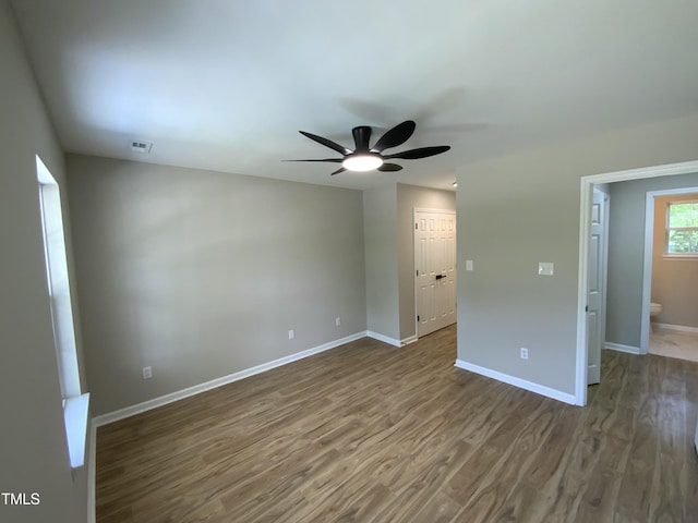 spare room with baseboards, ceiling fan, visible vents, and dark wood-type flooring